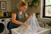 A woman washing a plastic shower curtain with a brush.