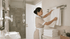 A maid putting new towels in the bathroom.