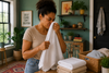 A woman  sniffing the towel with a sour smell.