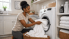 A black woman doing the laundry of white towels.