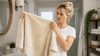 Blonde woman holding a yellowish towel.