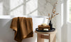 Turkish Cotton vs. Waffle Weave bath towels draped over a bathtub, showcasing luxurious textures and colors.