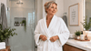 A blonde woman in the bathroom with a white robe.