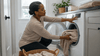 A black woman setting up the washing machine.