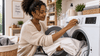 A black woman setting the washing machine temperature to wash towels.