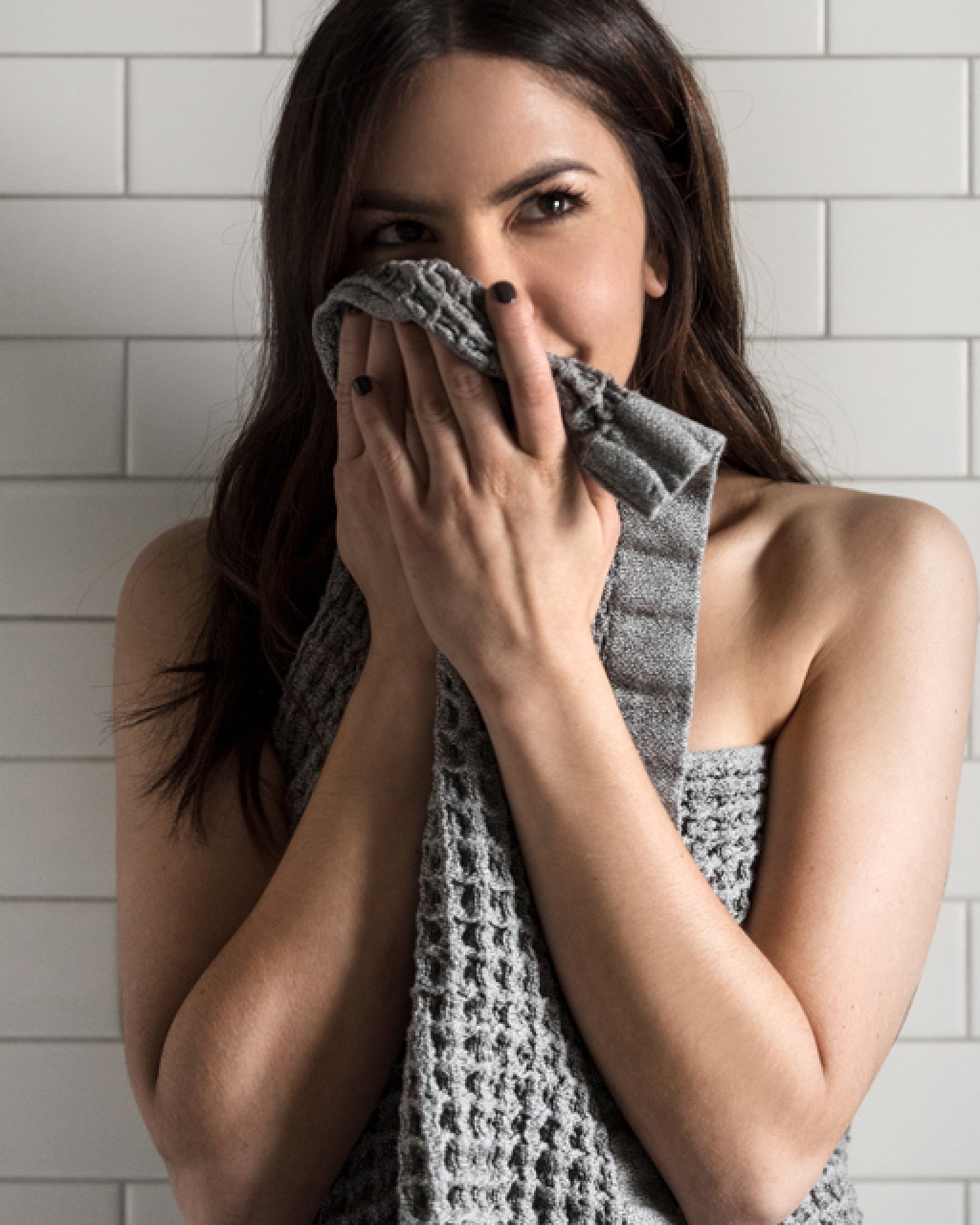 A woman wrapped in a Onsen Waffle towel in Cinder Grey #color_cinder-grey