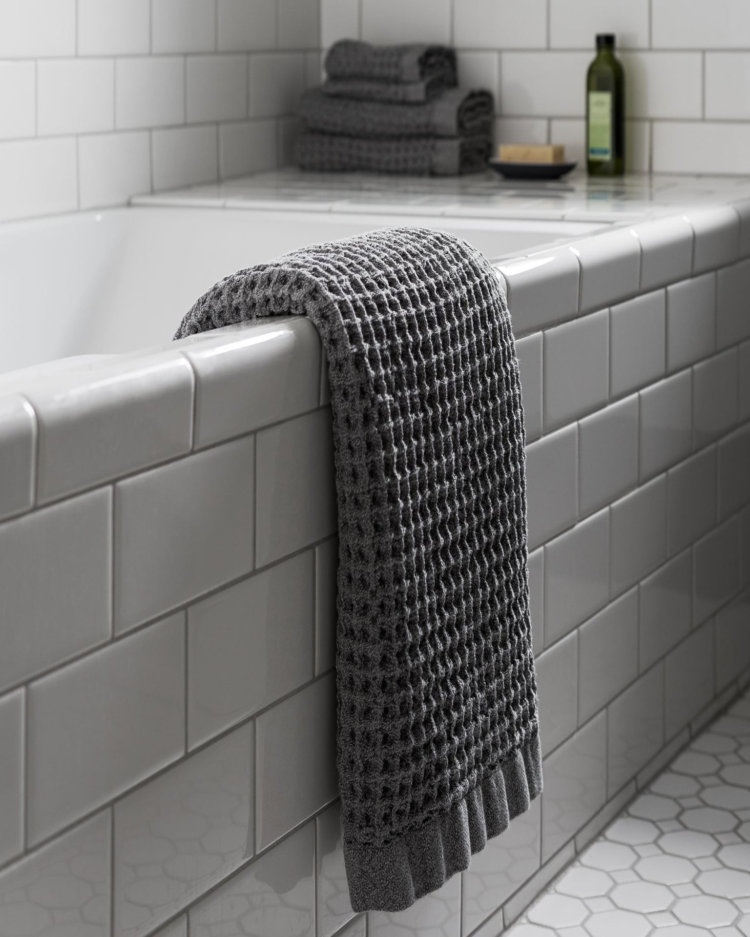 Onsen Waffle Towel in Cinder Grey over a bathtub #color_cinder-grey