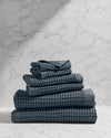 Stack of dark gray textured towels on a marble surface