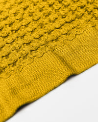 A close-up image of the Ochre Waffle Towel on a white background. 