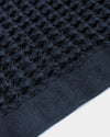 A close-up image of the ONSEN Twilight Blue Waffle Towel on a white background. 