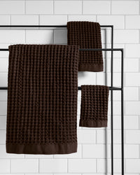 The ONSEN Brown Waffle Bath Sheet Set on a towel rack.