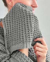 A lady using the ONSEN Cinder Grey Waffle Face Towel.