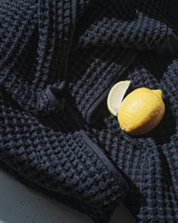 A close-up image of the ONSEN Twilight Blue Waffle Towel displayed with a lemon and a slice.